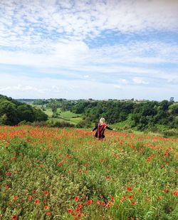 Rear view of person on poppy field against sky