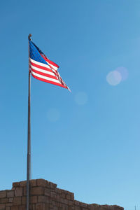 Flag of the united states waving in blue sky with flare. usa