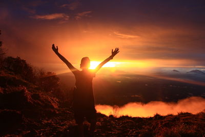 Silhouette person standing on field against sky during sunset