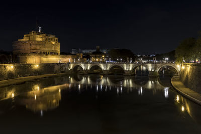 Illuminated bridge over river against sky at night