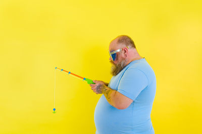Side view of a man against yellow background
