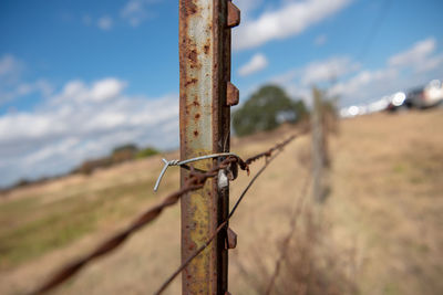 Close-up of barbed wire fence on field