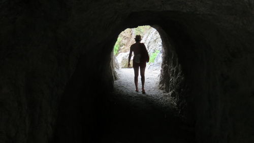 Rear view of woman standing in cave