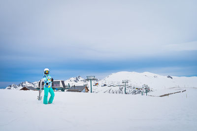 Skier looking at camera on the top of snowy pyrenees mountains with a ski lift in background andorra