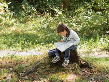 Little explorer on hike in forest.boy with binoculars reads map.outdoor leisure activity for child.