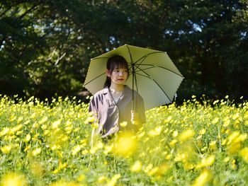 Woman holding umbrella on field