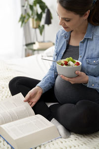 Pregnant woman eating salad at home