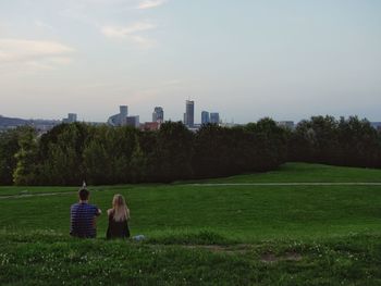 Rear view of couple sitting on farm against sky