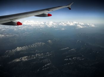 Airplane flying over mountains against sky