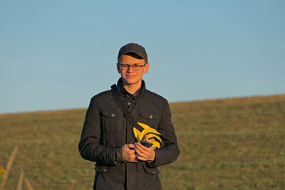 Portrait of man standing on field against clear sky