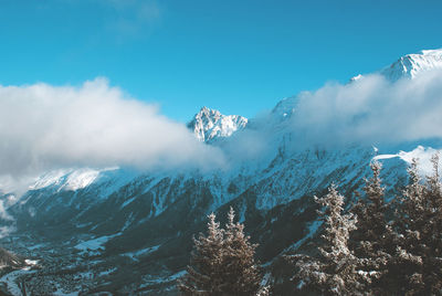 Low angle view of snow covered mountain against blue sky