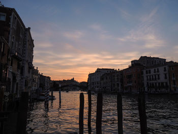 Canal amidst buildings against sky during sunset