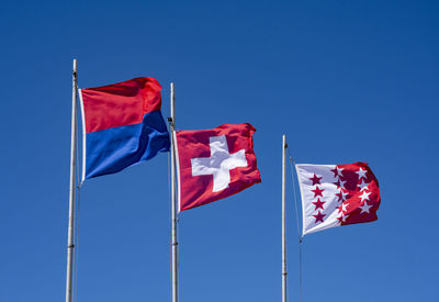 Low angle view of flags against clear blue sky