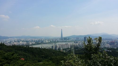 Distant view of lotte world tower in city against sky on sunny day