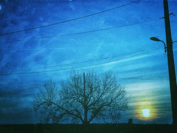 Low angle view of bare tree against cloudy sky