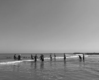 People on beach against clear sky