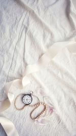 Directly above shot of pocket watch and ribbon on bed at home