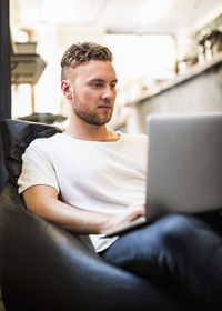 Young businessman using laptop while sitting on bean bag in new office