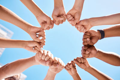 Low angle view of hand holding heart shape against sky