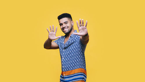 Portrait of young man standing against yellow background