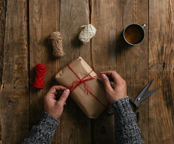 Top view of a man's hands packing a gift on a wooden table