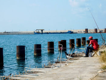 Rear view of man standing on railing against sea