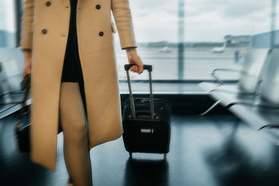 Midsection of woman with luggage at airport