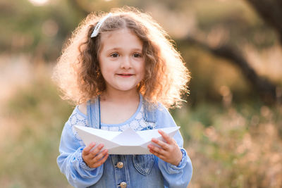 Smiling girl holding paper boat