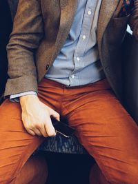 Midsection of man sitting outdoors