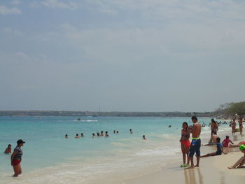 People enjoying at beach against sky