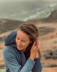 Smiling young woman standing on rock at beach