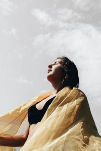 Low angle view of woman looking at camera against sky