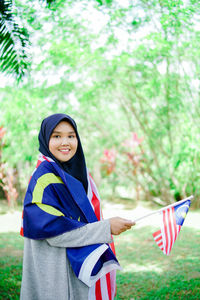 Muslim woman happy holding a malaysian flag. malaysia independence day.