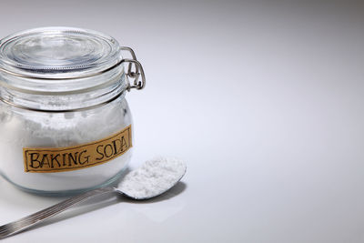 Close-up of baking soda with spoon on white background