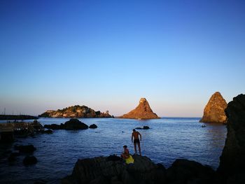 Panoramic view of rocks in sea against clear blue sky