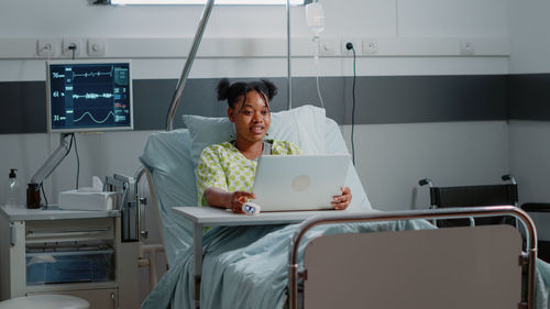 Young woman using mobile phone while sitting on bed at home