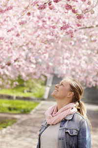 Smiling woman looking at cherry blossoms