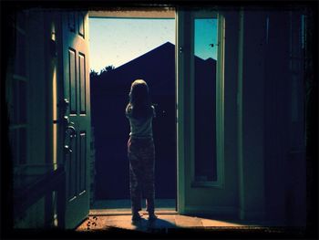Full length rear view of girl standing at entrance at home