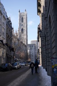 Rear view of people walking on street amidst buildings in city