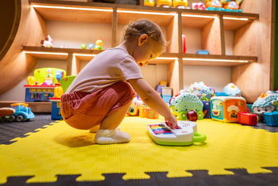 Side view of cute boy playing with toy blocks at home