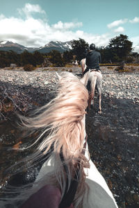 Rear view of man riding motorcycle on landscape against sky