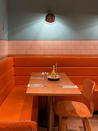 Empty chairs and table against illuminated wall at home