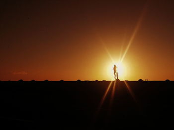 Silhouette man standing against orange sky during sunset