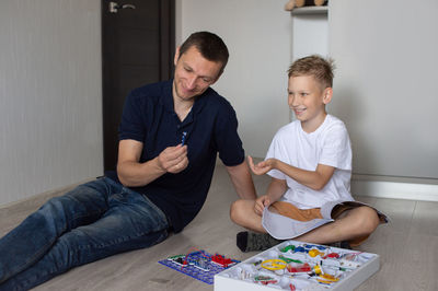 White t-shirt, electrical designer, lots of details, boy and man, dad and son, sit on the floor