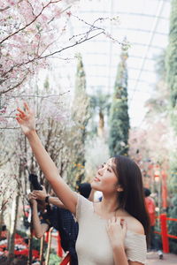 Young woman looking at trees in park