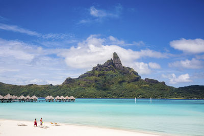 People on beach by mountain against sky