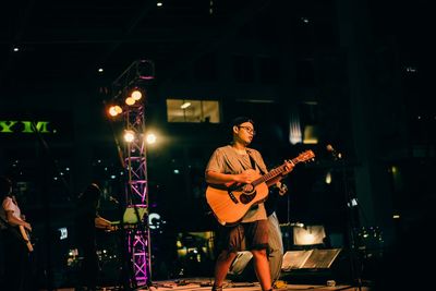 Full length of man playing guitar at night