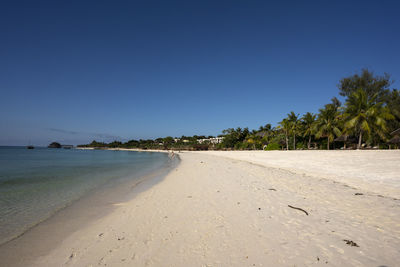 Scenic view of beach against clear blue sky