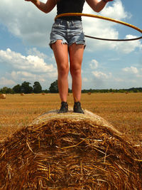 Low section of a woman on hay bale