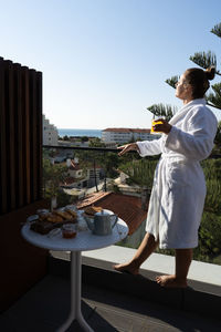 Rear view of woman standing by table against sky